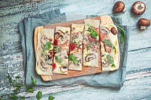 Freshly baked flammkuchen, traditional french tarte flambee or german pizza in a vegetarian recipe with mushrooms, cream cheese,