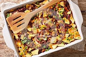 Freshly baked frito pie with ground beef, cheese, corn, beans and chips close-up in a baking dish. Horizontal top view