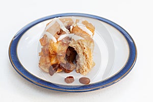 Freshly baked fruity chelsea bun on a plate with fruit. Wide focus.