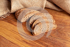 Freshly baked homemade bread with bran on a wooden background and burlap cut into slices. Foodphoto. photo