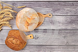 Freshly baked homemade bread, french sourdough baguette with crispy crust and ears of rye and wheat on wooden background with