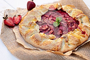 Freshly baked homemade galette or open strawberry pie and fresh mint leaves, summer food. Soft selective focus