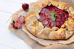 Freshly baked homemade galette or open strawberry pie and fresh mint leaves, summer food. Soft selective focus