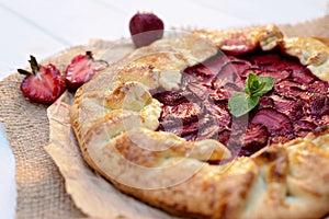 Freshly baked homemade galette or open strawberry pie and fresh mint leaves, summer food. Soft selective focus