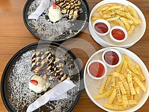 freshly baked homemade heart shaped Belgian waffles, covered with chocolate syrup and vanilla ice cream with sliced of straw berry