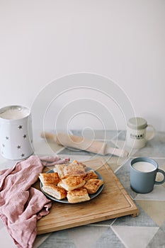 freshly baked homemade pastry on kitchen table. breakfast with puff buns and a glass of milk