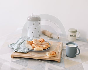 freshly baked homemade pastry on kitchen table. breakfast with puff buns and a glass of milk