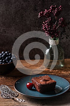 Freshly baked homemade vegan chocolate brownie served with a cherry and blueberries