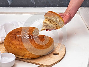 Freshly baked homemade wholegrain flour bread cut, the girl s hand treats a piece of sliced bread