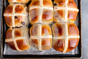 Freshly baked hot cross buns with raisins on a baking tray. Traditional English American Easter yeast pastry