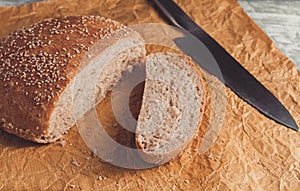 Freshly baked loaf of wholemeal bread with bran on baking paper. Sliced by knife