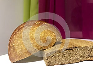 Freshly baked loaves of bread with a ruddy crust lie on the table. Visible slice loaf