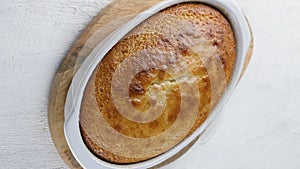 Freshly baked mannik, semolina cake or pie in a baking dish is puting on a wooden board on the table. Cooking stage