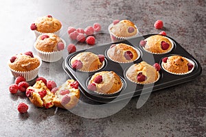 Freshly baked muffins with raspberries and white chocolate close-up in a muffin pan. Horizontal