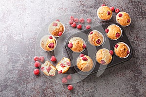 Freshly baked muffins with raspberries and white chocolate close-up in a muffin pan. Horizontal top view
