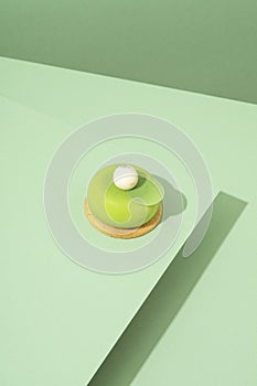 freshly baked pastry with green and white icing, sitting atop a green-hued surface