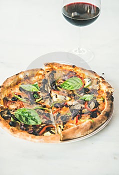 Freshly baked pizza with vegetables, basil and glass of wine