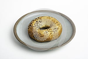 A Freshly Baked Single Bagel On A Ceramic Plate