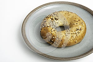 A Freshly Baked Single Bagel On A Ceramic Plate