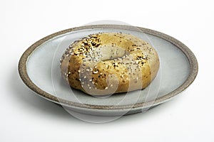 A Freshly Baked Single Bagel On A Ceramic Plate