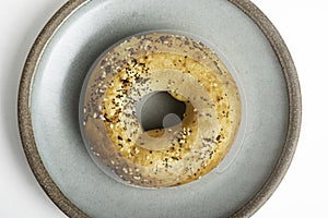 A Freshly Baked Single Bagel On A Ceramic Plate