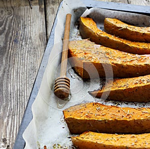 Freshly baked slices of pumpkin on a baking tray with dried rose