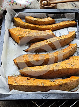 Freshly baked slices of pumpkin on a baking tray with dried rose