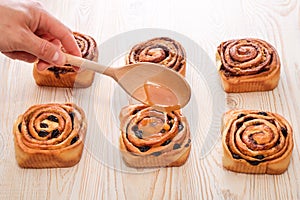 Freshly baked sweet bun with raisins and cinnamon on wooden table. Glazing a Cinnabons won. Homemade traditional bakery