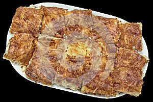 Freshly Baked Traditional Serbian Crumpled Cheese Pie Gibanica Served on Oval Ceramic Tray Isolated on Black Background