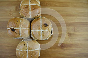 Freshly baked warm hot cross buns laid on a wood cutting board with space