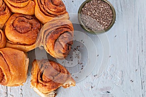 Freshly baked wheat buns with poppy seeds on blue wooden background