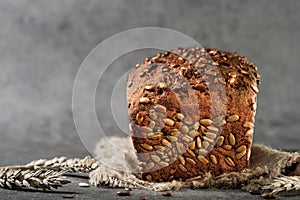 Freshly baked wheat and rye bread with seeds on burlap, close-up with selective focus. Fermented healthy bread, gray background