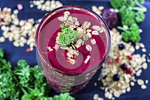 Freshly blended berry smoothie in a glass and granola on dark rustic wooden background. Selective focus, copy space