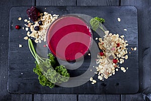 Freshly blended berry smoothie in a glass and granola on dark rustic wooden background. Selective focus, copy space