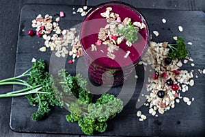 Freshly blended berry smoothie in a glass and granola on dark rustic wooden background. Selective focus, copy space