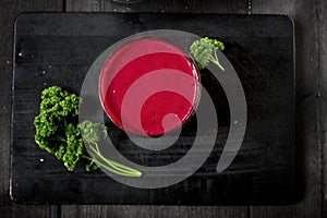 Freshly blended berry smoothie in a glass and granola on dark rustic wooden background. Selective focus, copy space