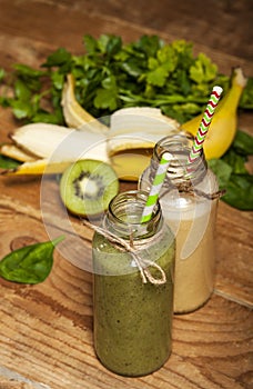 Freshly blended green and banana smoothies in glass bottles with straws.