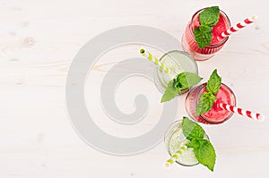 Freshly blended green and red fruit smoothie in glass jars with straw, mint leafs, top view.