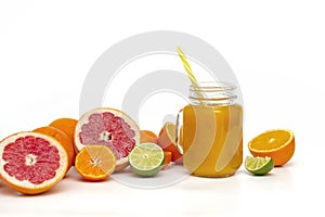 Freshly blended yellow and orange fruit smoothie in glass jar. Glass jar mugs with orange health smoothie, lime, grapefruit, lemon