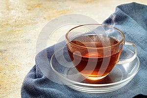 Freshly brewed black tea in a glass cup, steaming hot drink on a