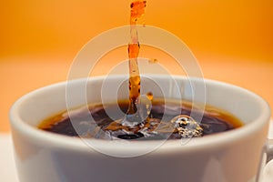 freshly brewed coffee pours into a white cup on the background