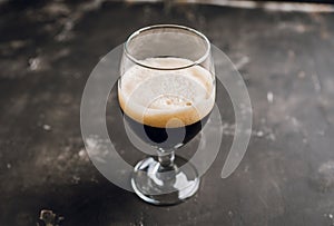 Freshly brewed dark beer on the black rustic background