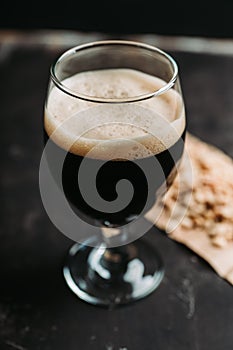 Freshly brewed dark beer on the black rustic background