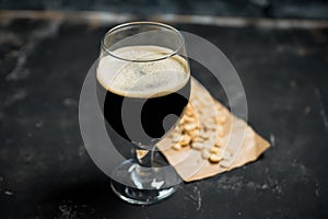 Freshly brewed dark beer on the black rustic background