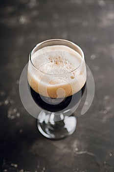 Freshly brewed dark beer on the black rustic background