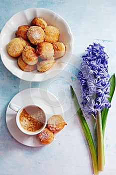 Freshly brewed espresso, small homemade doughnuts with icing sugar