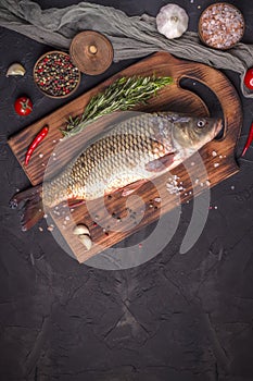 Freshly caught carp with scales, ready to cook on a wooden board. Top view, copy space