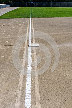 Freshly chalked baseline, with third base plate, running out to the 300 yards sign, empty baseball field on a sunny day