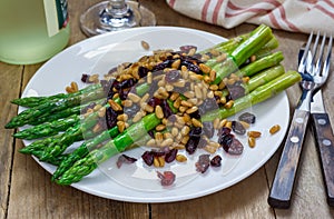 Freshly cooked asparagus appetizer with pine nuts and cranberries