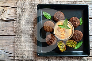 Freshly cooked falafel on a wooden table with tahini sauce.Eastern vegetarian meal of chickpea.